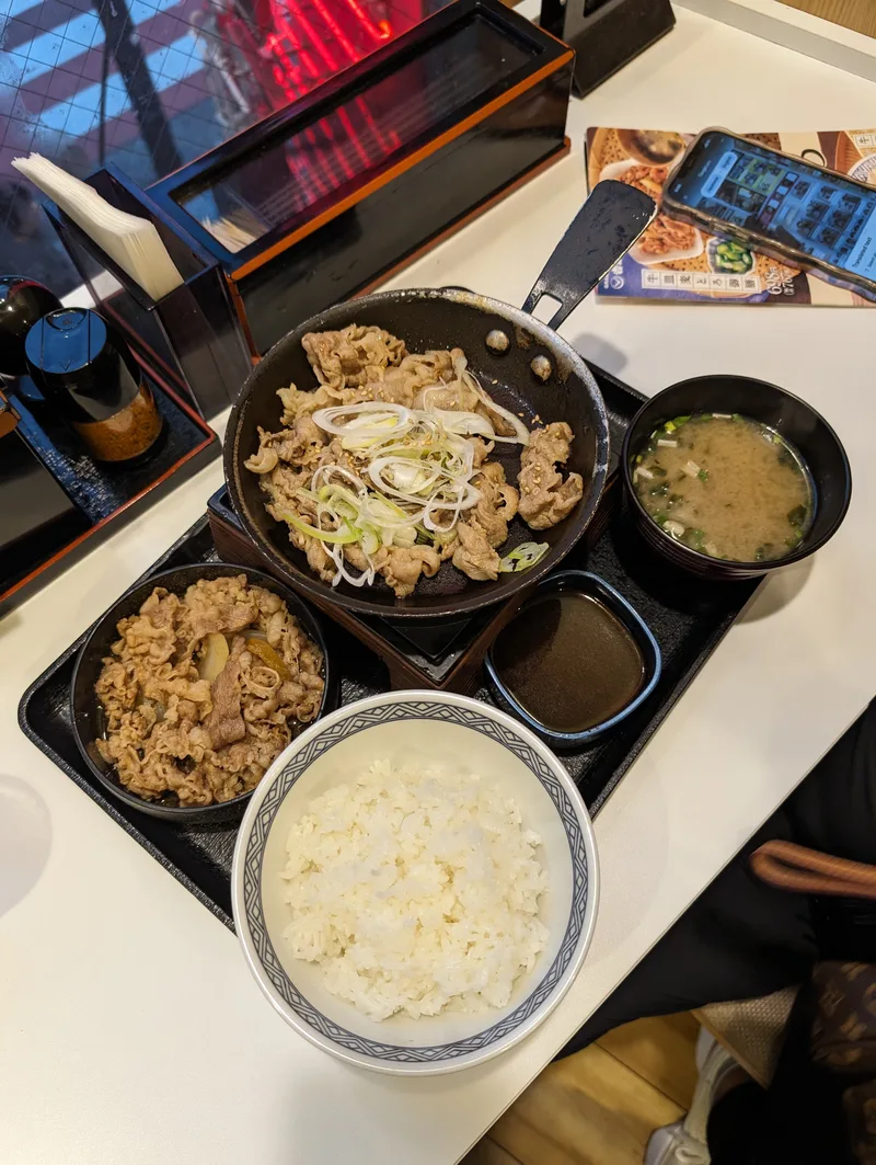 Japanese meal set with sizzling pork, beef and rice bowl, and miso soup at Yoshinoya in Shibuya, Tokyo, Japan.