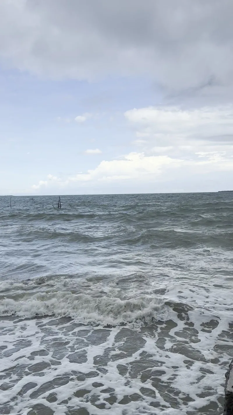 Ocean waves breaking on a sandy shore in Palawan under a partly cloudy sky