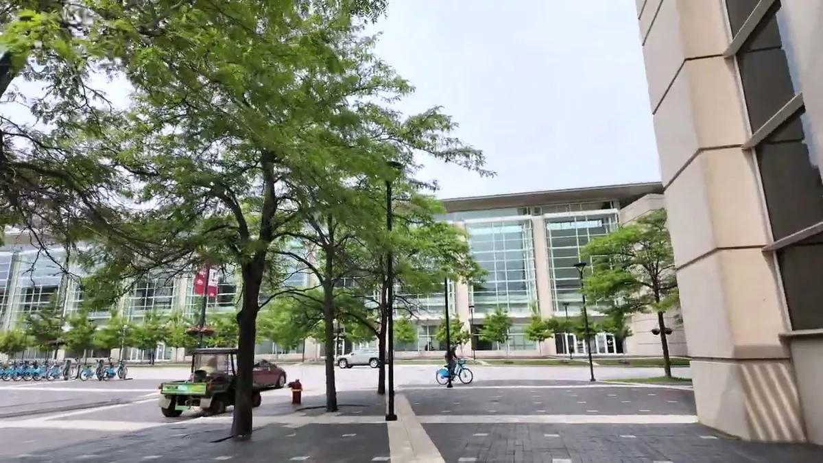 Modern glass buildings and tree-lined street in downtown Chicago, Illinois under a cloudy summer sky
