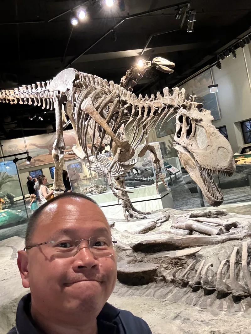 Man taking a selfie with a Tyrannosaurus Rex skeleton at the Field Museum in Chicago, Illinois
