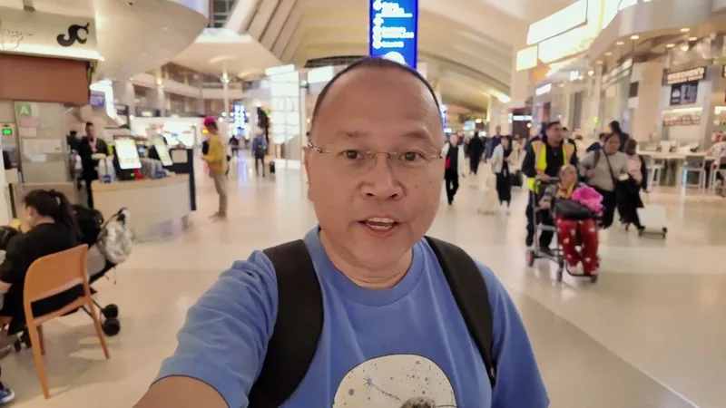 Man in blue shirt taking a selfie video in the busy main terminal at Los Angeles International Airport (LAX)