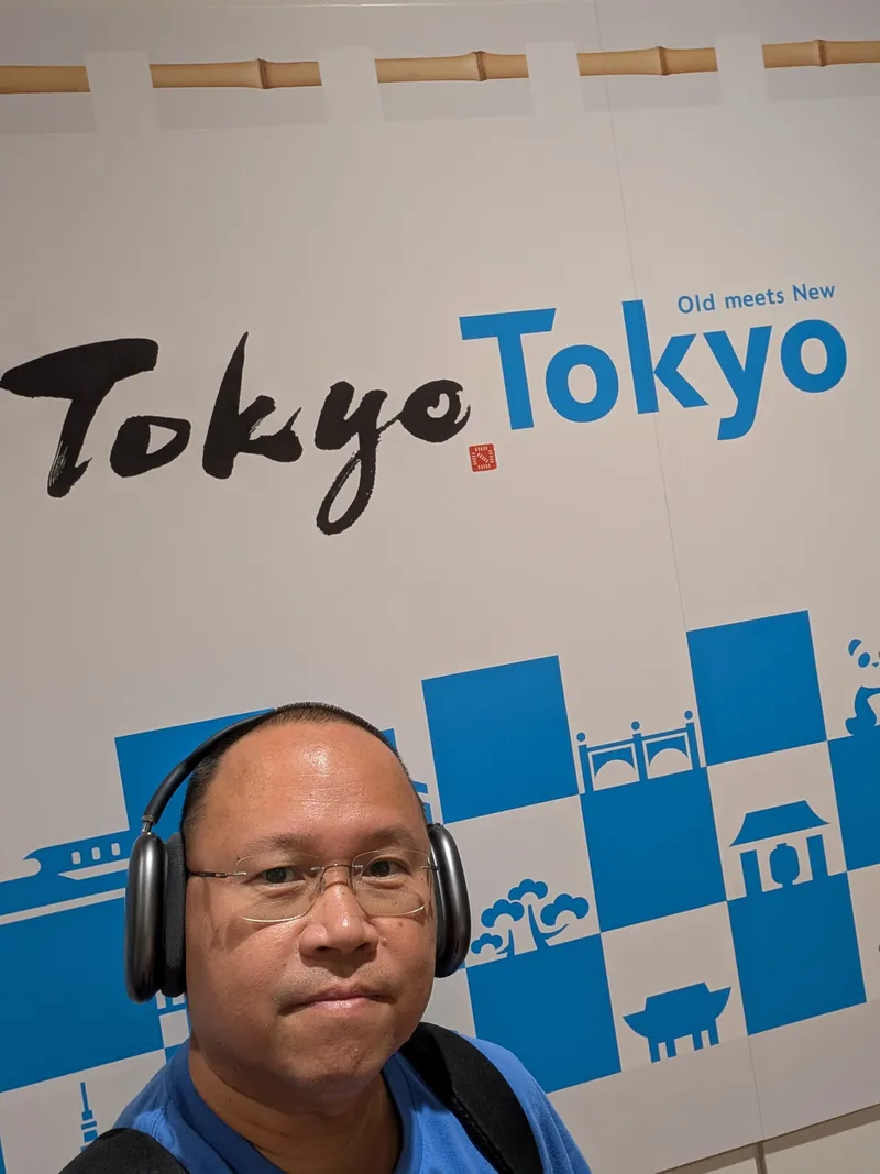 Man taking selfie in front of the Tokyo Old Meets New welcome sign at Haneda Airport, Tokyo, Japan