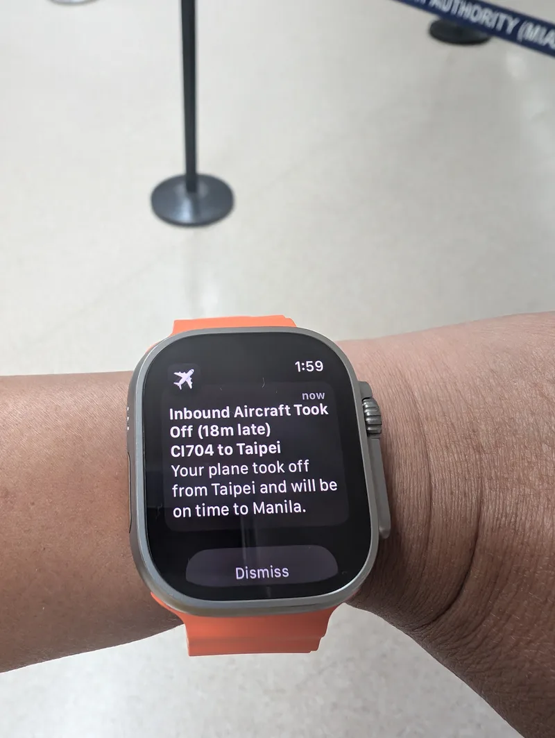 Apple Watch Ultra displaying a flight tracking notification for China Airlines CI704 from Taipei, showing an 18-minute late departure but on-time arrival at Manila, Philippines.