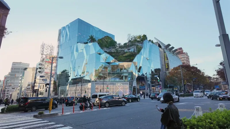 Faceted glass Dior building in Omotesando with a green rooftop garden of trees and shrubs above the DIOR storefront against a blue sky in Tokyo, Japan
