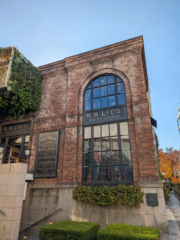 Brick R.R.L. & Co. Ralph Lauren building with large arched windows and green ivy climbing the facade in Harajuku, Tokyo, Japan
