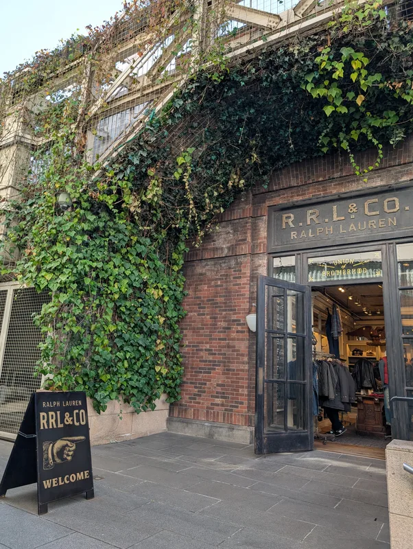 Open entrance to the R.R.L. & Co. Ralph Lauren store with a Welcome sandwich board and ivy on the brick facade in Harajuku, Tokyo, Japan