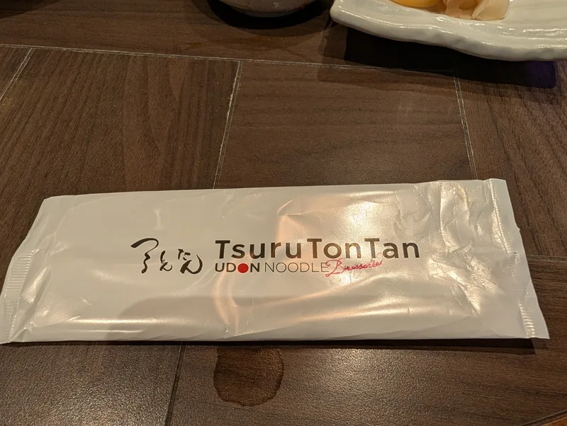 Tsuru Ton Tan udon restaurant chopstick sleeve on a dark wooden table in Shibuya, Tokyo, Japan