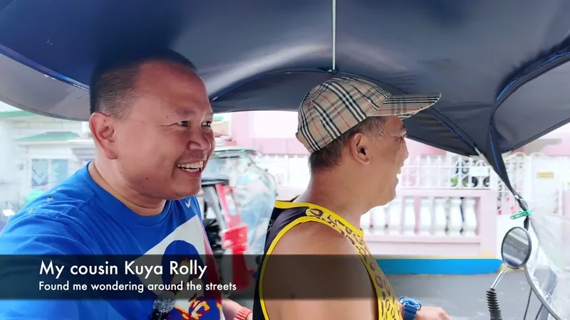 Two men inside a vehicle, one smiling at camera, the other in a plaid cap looking away.