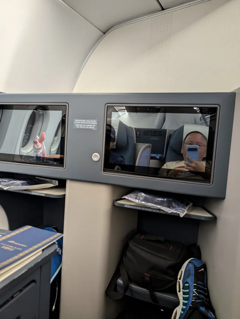 Airplane business class seat with two entertainment screens aboard a Philippine Airlines flight from Tokyo Haneda Airport, Japan.