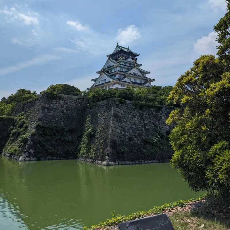 Corner view of Osaka Castle showing stone walls and green moat in Osaka, Japan.