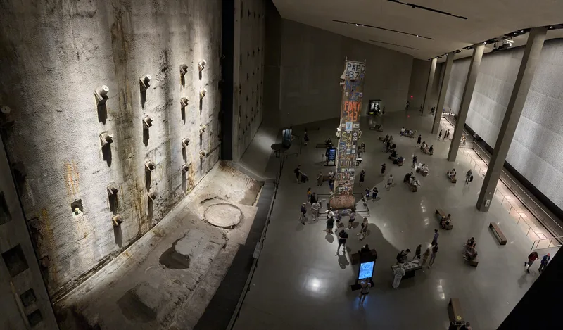 The main hall — built around what's left of the original towers Overhead view of 9/11 Memorial Museum main hall with slurry wall and visitors