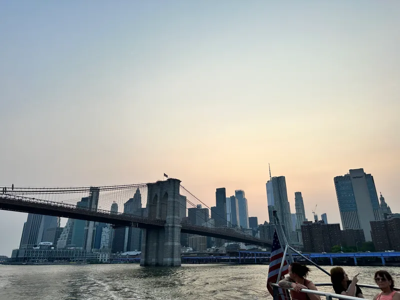 Manhattan skyline from the boat — that American flag in the foreground Brooklyn Bridge and lower Manhattan skyline from boat at sunset with American flag