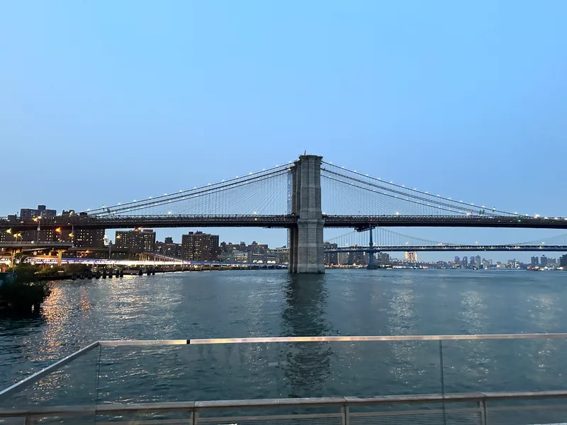The bridges lit up with the skyline — worth staying out late for Brooklyn Bridge and Manhattan Bridge over East River with illuminated NYC skyline at dusk