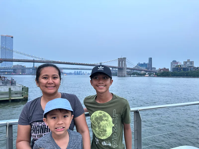 Mother and two sons on pier with Brooklyn and Manhattan Bridges