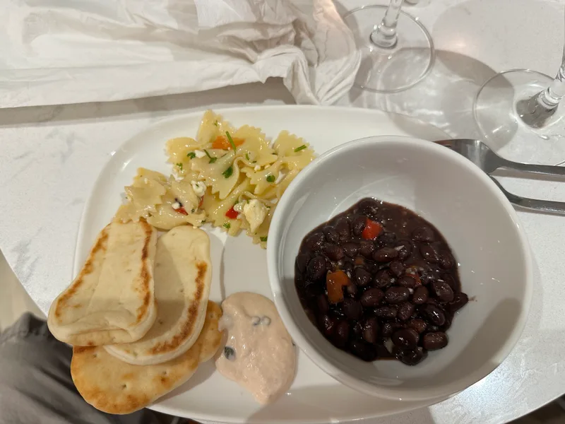 Delta Sky Club meal with pasta salad, black beans, and naan bread Delta Sky Club meal with pasta salad, black beans, and naan bread