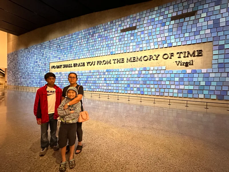 The memorial wall with the Virgil quote — 'No day shall erase you from the memory of time' Family at 9/11 Museum, blue tiled memorial wall with Virgil quote
