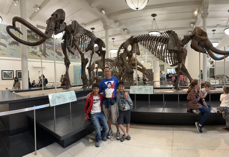 Family poses with woolly mammoth skeletons at natural history museum