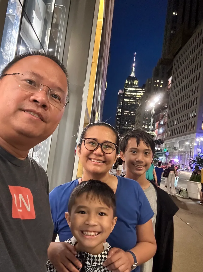 Family selfie on NYC street at night with Empire State Building