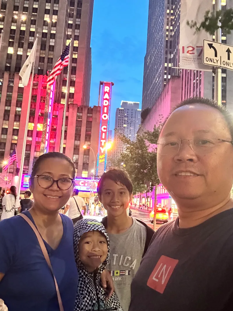 Radio City Music Hall — those neon lights hit different in person Family selfie in front of Radio City Music Hall at dusk with neon lights