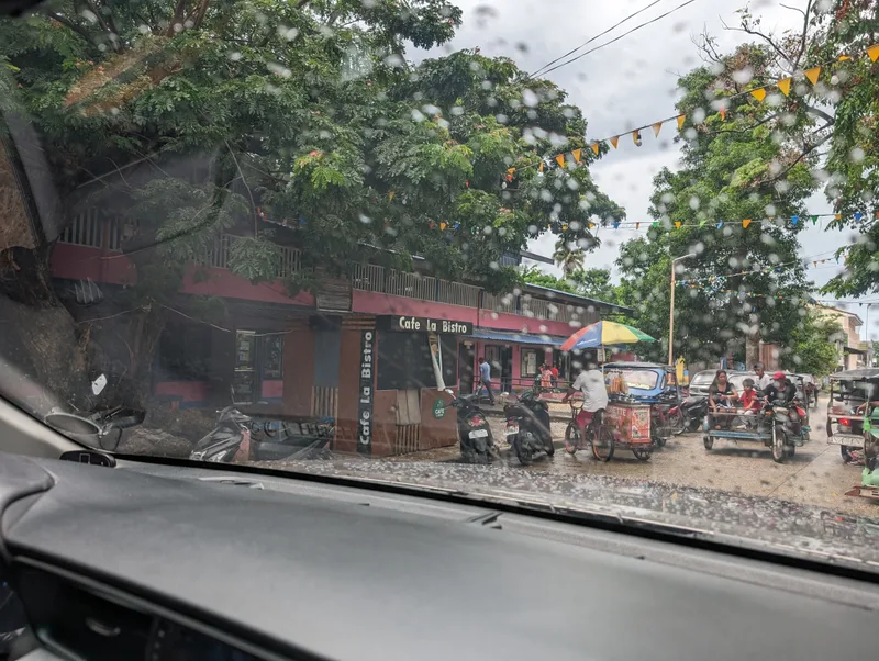 Street scene with Cafe La Bistro and tricycles through a rainy windshield in Roxas Palawan Philippines