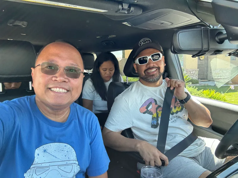 Three people in a car smiling on the way to Ontario International Airport, California