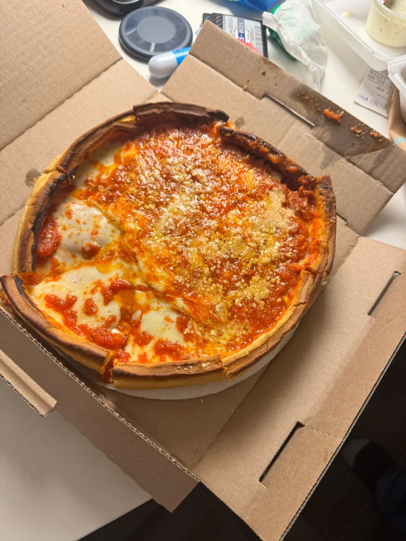 Chicago deep-dish pizza in a cardboard delivery box, golden crust with melted cheese and tomato sauce, Chicago, Illinois