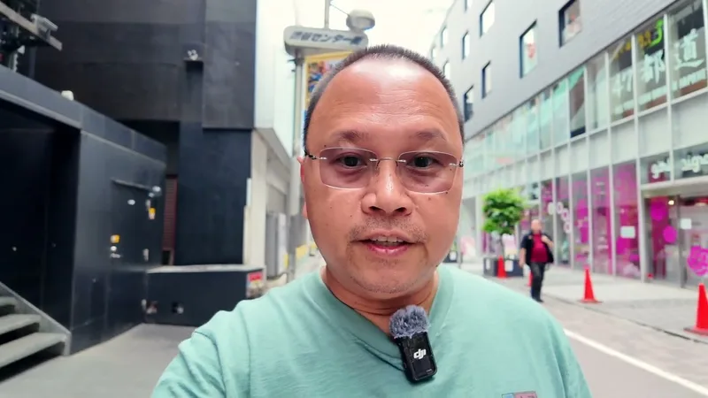 Man taking a selfie video on a street in Shibuya, Tokyo, Japan, at night, shops and an alleyway visible in the background.