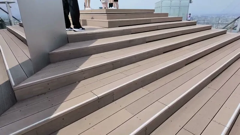 Tiered wooden seating on the outdoor rooftop of Shibuya Sky in Shibuya, Tokyo, Japan, with the city skyline in the background.