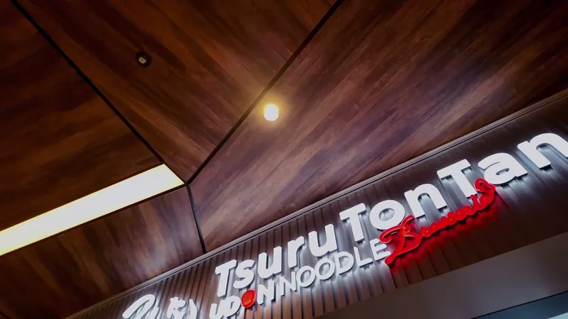 Tsuru Ton Tan Udon Noodle Brasserie neon sign with red lettering and warm wooden ceiling at Shibuya Sky, Shibuya, Tokyo, Japan.