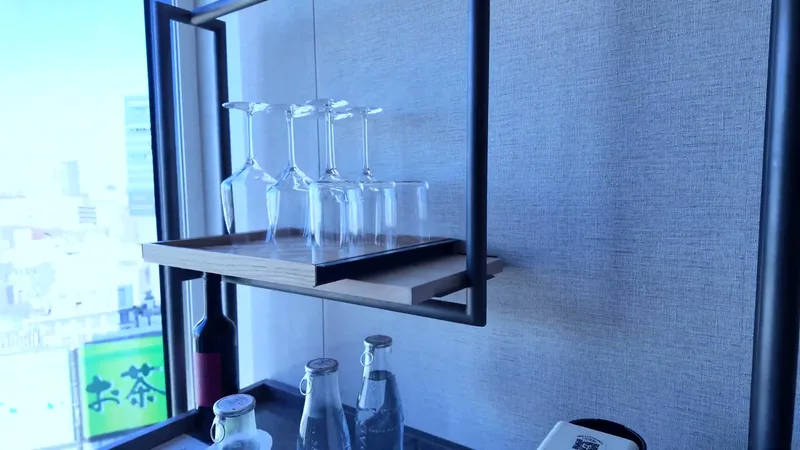 Complimentary water bottles and wine glasses on the minibar shelf at Hotel Indigo Shibuya, Tokyo, Japan