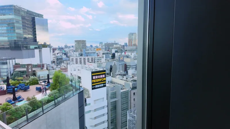 View of the Tokyo skyline from Hotel Indigo Shibuya's rooftop terrace with blue outdoor seating in Shibuya, Tokyo, Japan