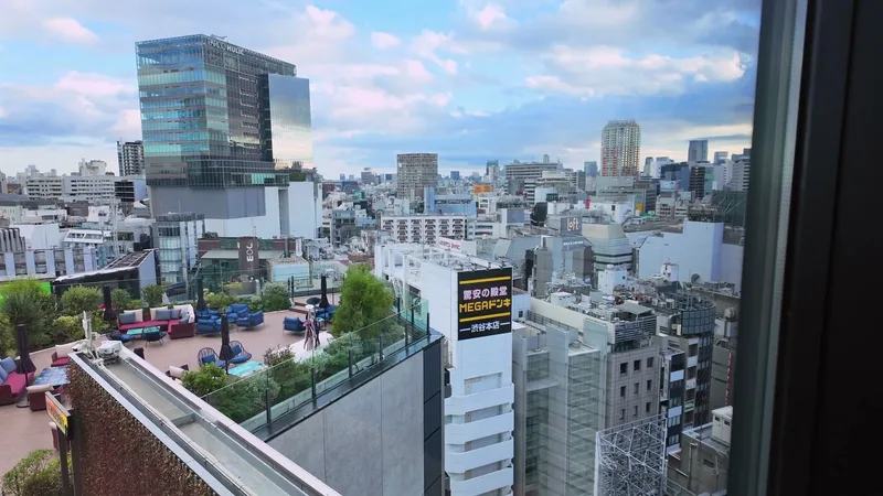 Panoramic view of the Tokyo cityscape from Hotel Indigo Shibuya's 12th floor reception area, with Mega Don Quijote sign visible below in Shibuya, Tokyo, Japan