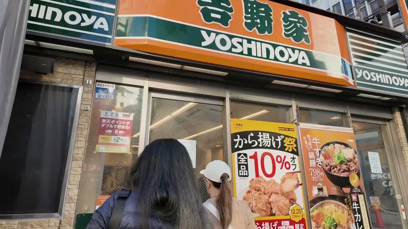 Close-up of the Yoshinoya entrance with promotional posters for karaage chicken and beef hot pot meals in Shibuya, Tokyo, Japan