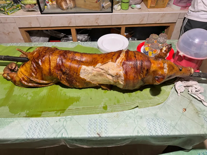 The lechon — they went all out Whole roasted pig lechon laid out on banana leaves ready to be served at a Filipino family gathering in Palawan