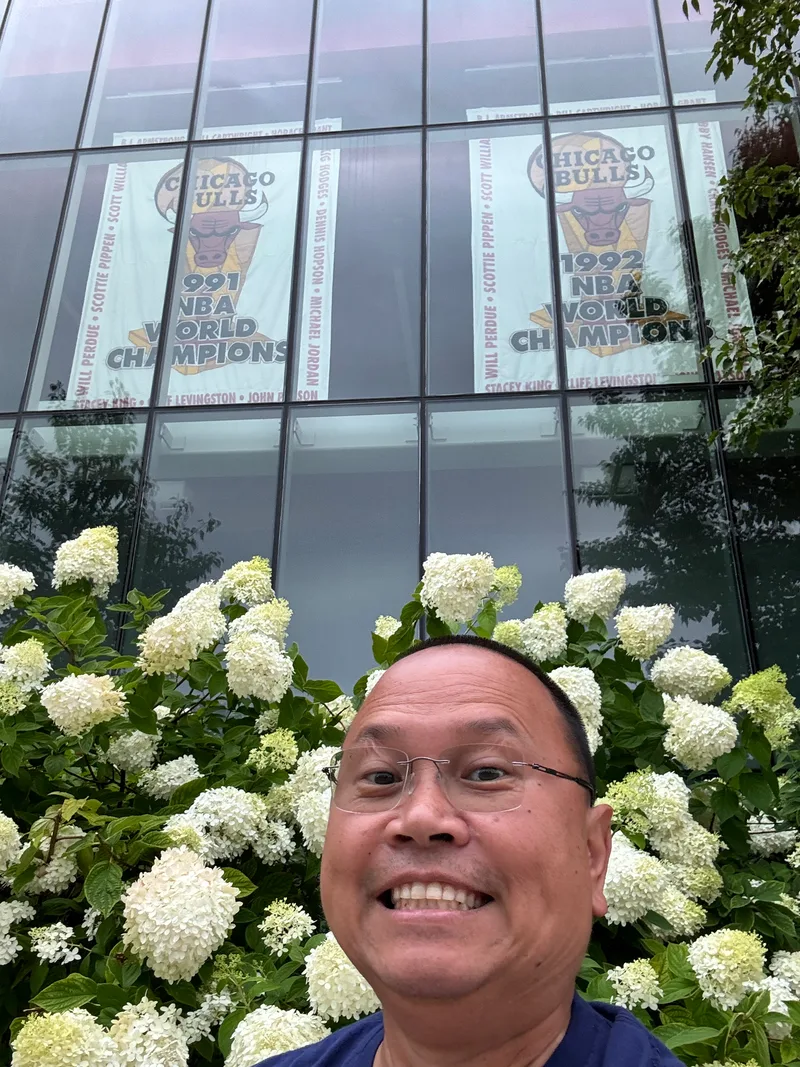 Man taking selfie in front of the Chicago Bulls 1991 and 1992 championship banners through glass at the United Center, Chicago, Illinois