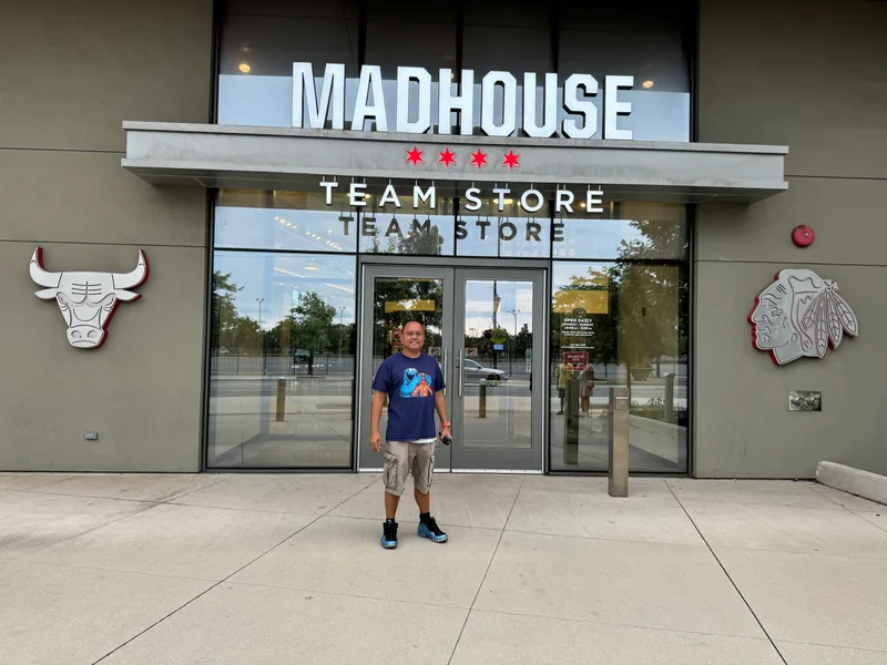 Man smiling in front of Madhouse Team Store entrance with Chicago Bulls and Blackhawks logos at the United Center, Chicago, Illinois