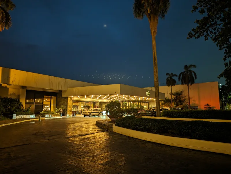 Sofitel Philippine Plaza entrance at dusk with warm overhead lights, a vintage car under the porte-cochère, and palm trees in Pasay, Metro Manila.